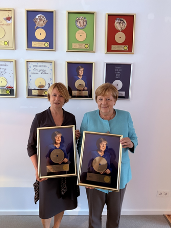 Corinna Harfouch, die das Hörbuch eingelesen hat, und Angela Merkel freuen sich über die Goldene Schallplatte.