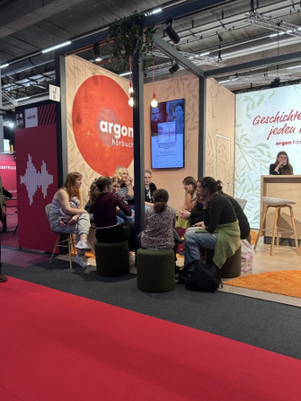 Menschengruppe sitzt am Stand des argon verlags auf der Frankfurter Buchmesse