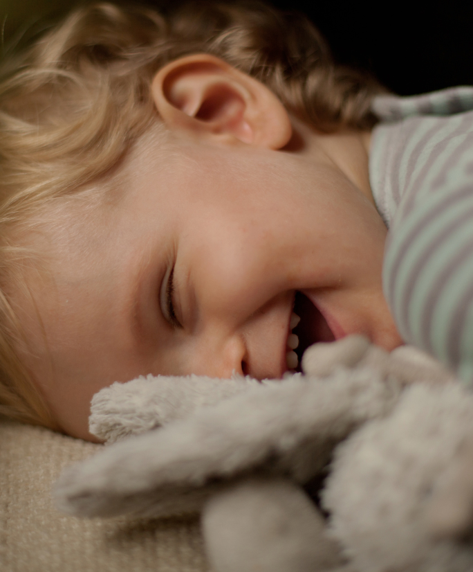 Kleines Kind lacht mit Kuschelhasen