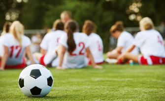 Frauenfußballmanschaft sitzt auf Spielfeld