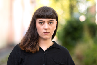 Autorinnenportrait Anna Yeliz Schente. Sie blickt ernst in die Kamera, der Hintergrund ist verschwommen.