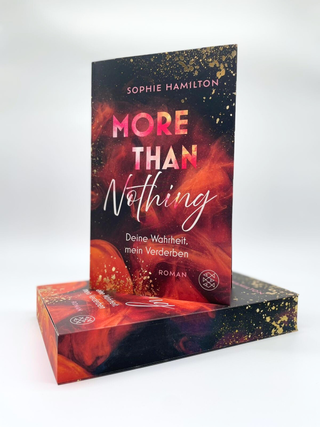 Das Buch »More Than Nothing« von Sophie Hamilton steht aufrecht vor einem liegenden Exemplar desselben Buches. Das Cover hat ein feuriges, rot-schwarzes Design mit goldenen Sprenkeln und trägt den Untertitel »Deine Wahrheit, mein Verderben«. Auch der Buchschnitt des liegenden Buches ist passend zum Cover farbig bedruckt.