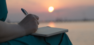 Frau schreibt in ihr Tagebuch während des Sonnenuntergangs