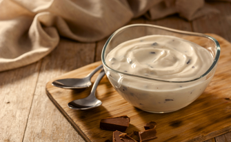 Stracciatella Gericht mit zwei Löffeln auf einem Holzbrettchen