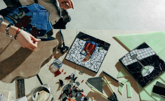 Mosaikbasteln mit Mosaiksteinen, Werkzeug und einer Person in der Ecke