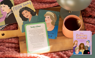 Ein gemütliches Arrangement auf einem Holztablett mit einer Tasse Tee und illustrierten Karten bekannter Persönlichkeiten wie Susan Sontag, Prinzessin Diana und Coco Chanel. Im Vordergrund liegt eine Infokarte zu Yoko Ono neben der lilafarbenen Box „Das Frauen Orakel“.