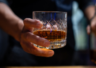 Eine Männerhand, die einen Whiskytumbler hält