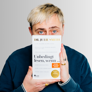 Ein Mann mit blondierten Haaren und einem Fleece-Pulli hält «Unbedingt lesen, wenn ...» von Dr. Julie Smith vor den Mund