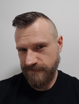 Timo Kümmel, ein Mann mit Bart, die Haare an den Seiten rasiert, oben zur Seite gekämmt.
